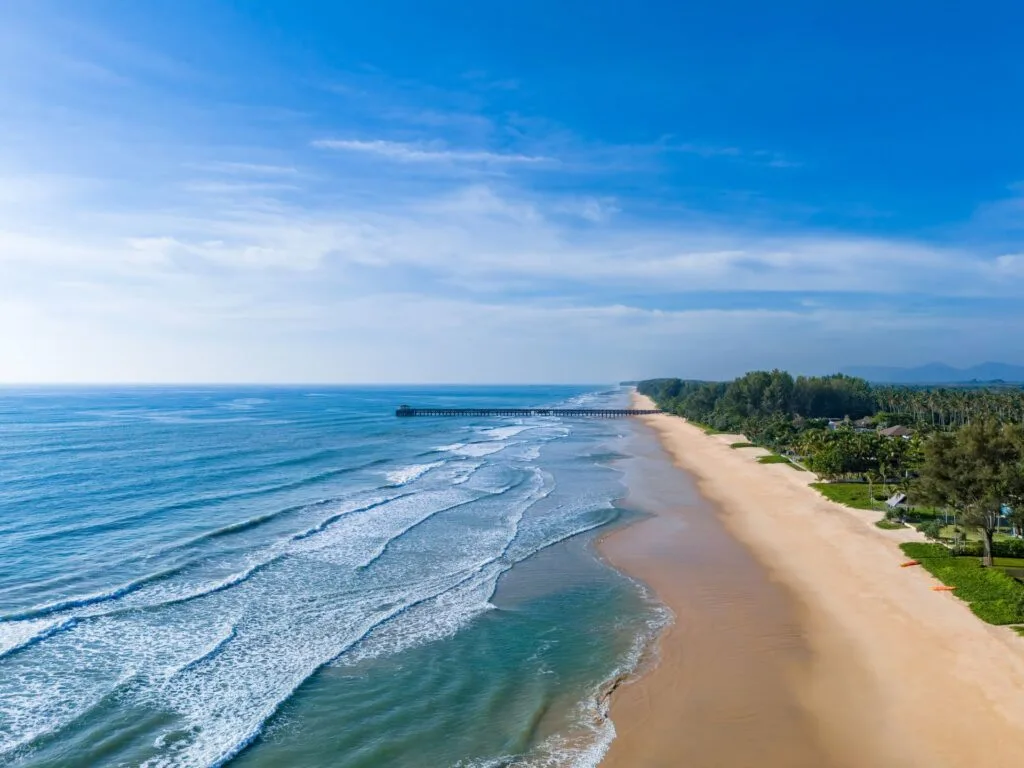 Aerial view of Natai Beach and Natai Pier in Phang Nga, Thailand, showing a long quiet shoreline north of Phuket Island.