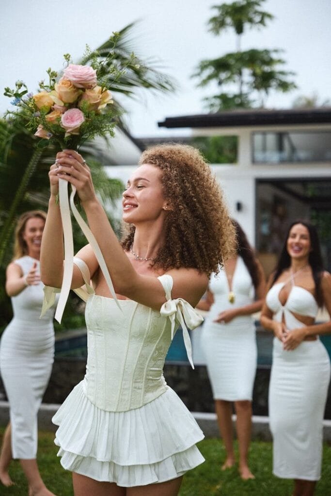 Bride tossing bouquet on the beach during a joyful wedding celebration at Twin Villas Natai