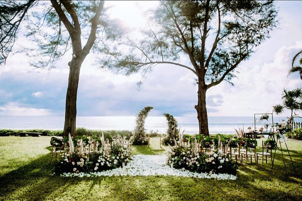 Wedding arch decorated with tropical flowers on the lawn of Twin Villas Natai, a Natai beachfront wedding villa