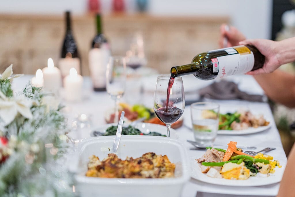 Red wine being poured during a festive holiday dinner at Twin Villas Natai, highlighting the warm, intimate dining experience offered at this beachfront Christmas villa in Thailand.
