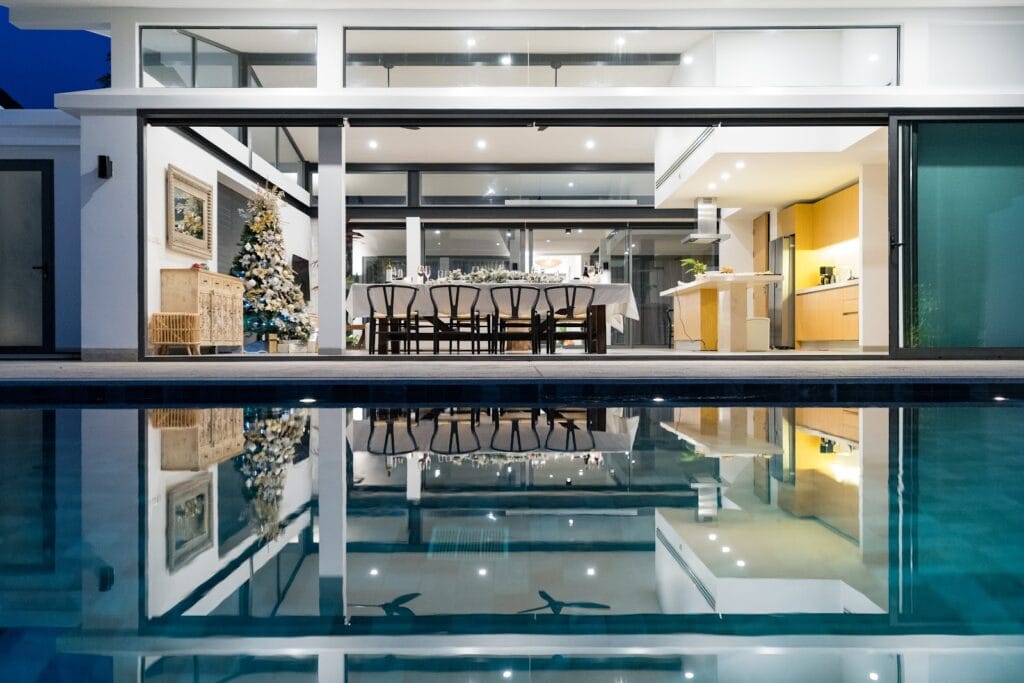 Elegant beachfront Christmas dinner setup at Twin Villas Natai, showcasing a decorated Christmas tree and festive dining table reflected in the private infinity pool of this luxury Christmas villa in Phuket.
