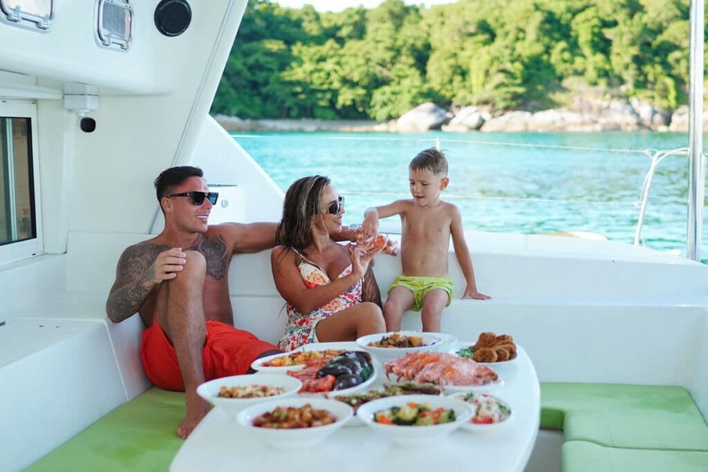 A family enjoying a gourmet seafood lunch on the deck of a private yacht, a comfortable and shaded setting for multigenerational groups.
