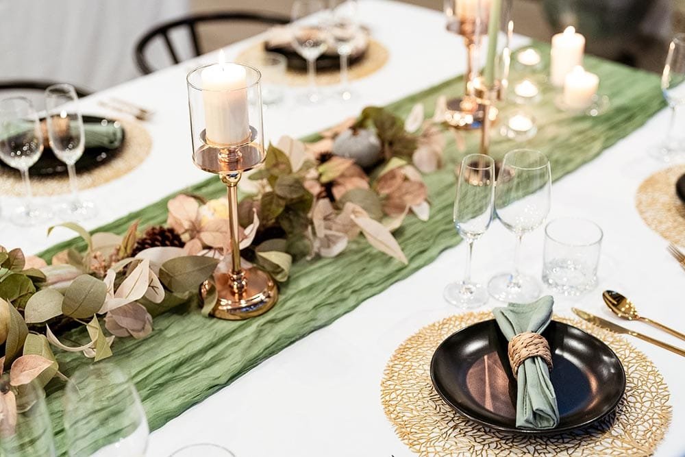Retreat Villas Near Phuket – A Private Beachfront Wellness Sanctuary at Twin Villas Natai | Twin Villas Natai Elegant candlelit dinner table setting with green runner, gold accents and floral arrangement prepared for a private retreat gathering at Twin Villas Natai