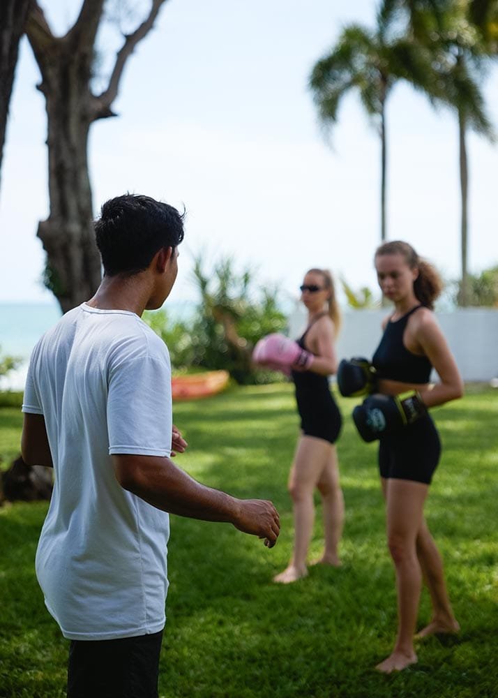 Retreat Villas Near Phuket – A Private Beachfront Wellness Sanctuary at Twin Villas Natai | Twin Villas Natai Muay Thai training session on a private villa lawn with instructor guiding participants during a retreat program.