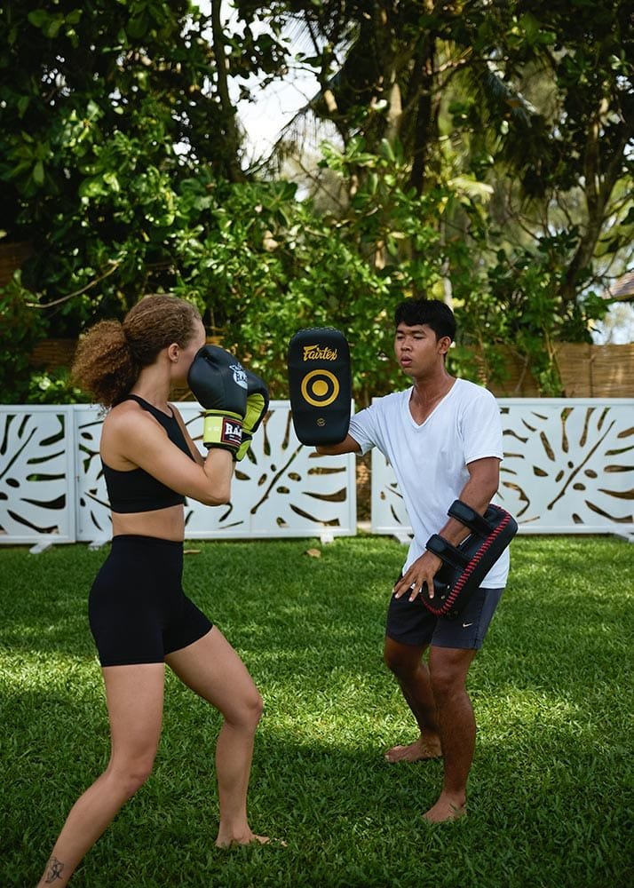 Retreat Villas Near Phuket – A Private Beachfront Wellness Sanctuary at Twin Villas Natai | Twin Villas Natai One-on-one Muay Thai pad training session with a local instructor in a tropical garden setting.