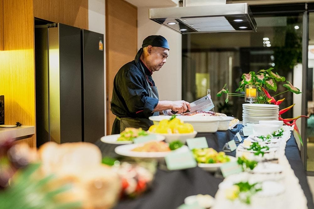 Retreat Villas Near Phuket – A Private Beachfront Wellness Sanctuary at Twin Villas Natai | Twin Villas Natai Private chef preparing a buffet-style dinner in a professional villa kitchen during a wellness retreat