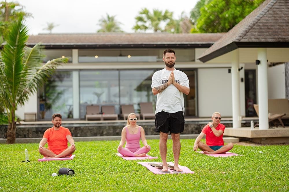 Retreat Villas Near Phuket – A Private Beachfront Wellness Sanctuary at Twin Villas Natai | Twin Villas Natai Small group yoga session on a private villa lawn, allowing focused practice in a quiet retreat setting near Phuket.